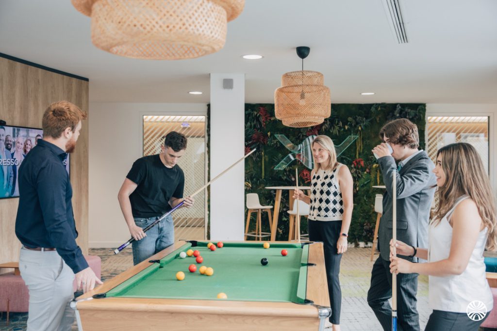 Groupe jouant au billard dans un bureau moderne.
